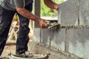 hand-of-worker-plastering-cement-on-brick-wall-at-construction-site+1