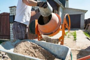 construction-worker-with-a-bucket-in-his-hands-loads-a-concrete-mixer-orange+1+1